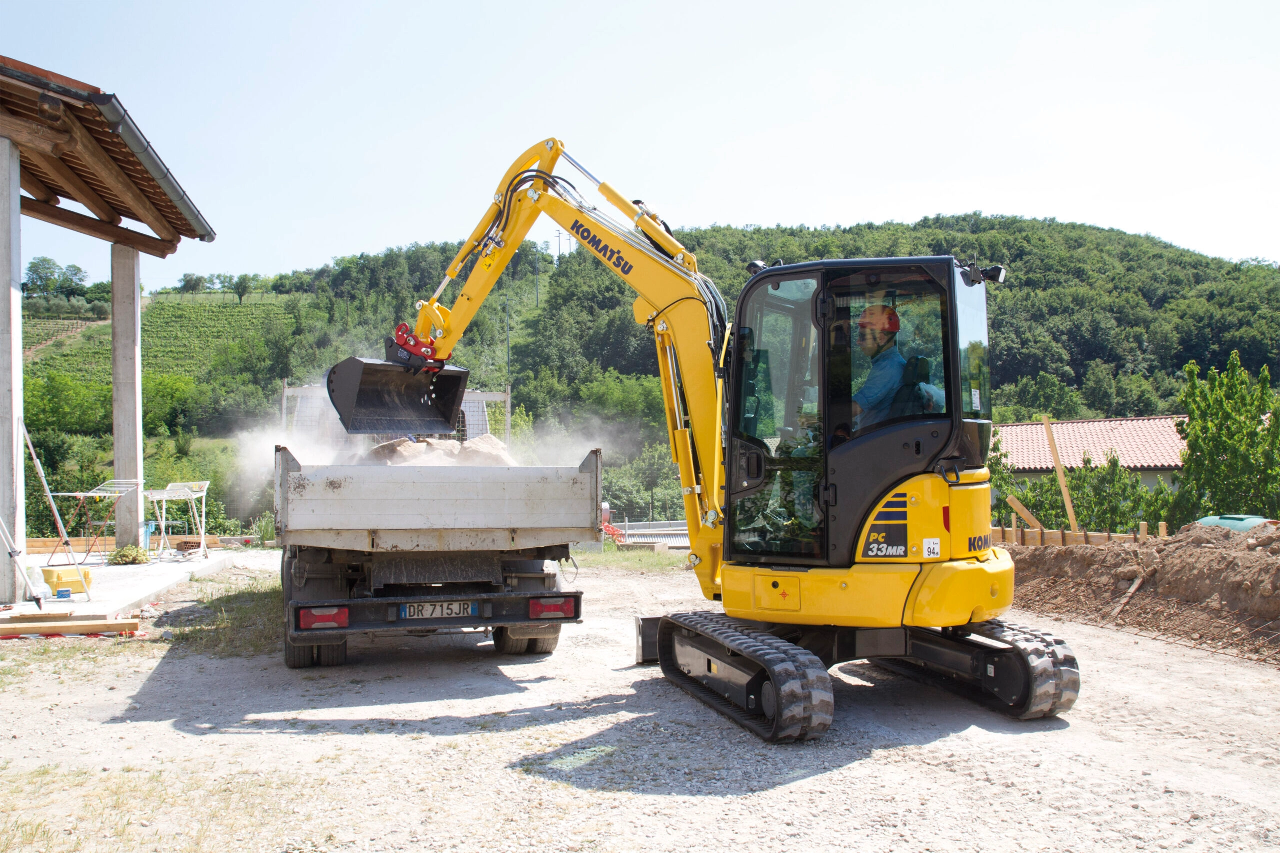 Komatsu PC33MR-5 häller sand i flaket på en truck