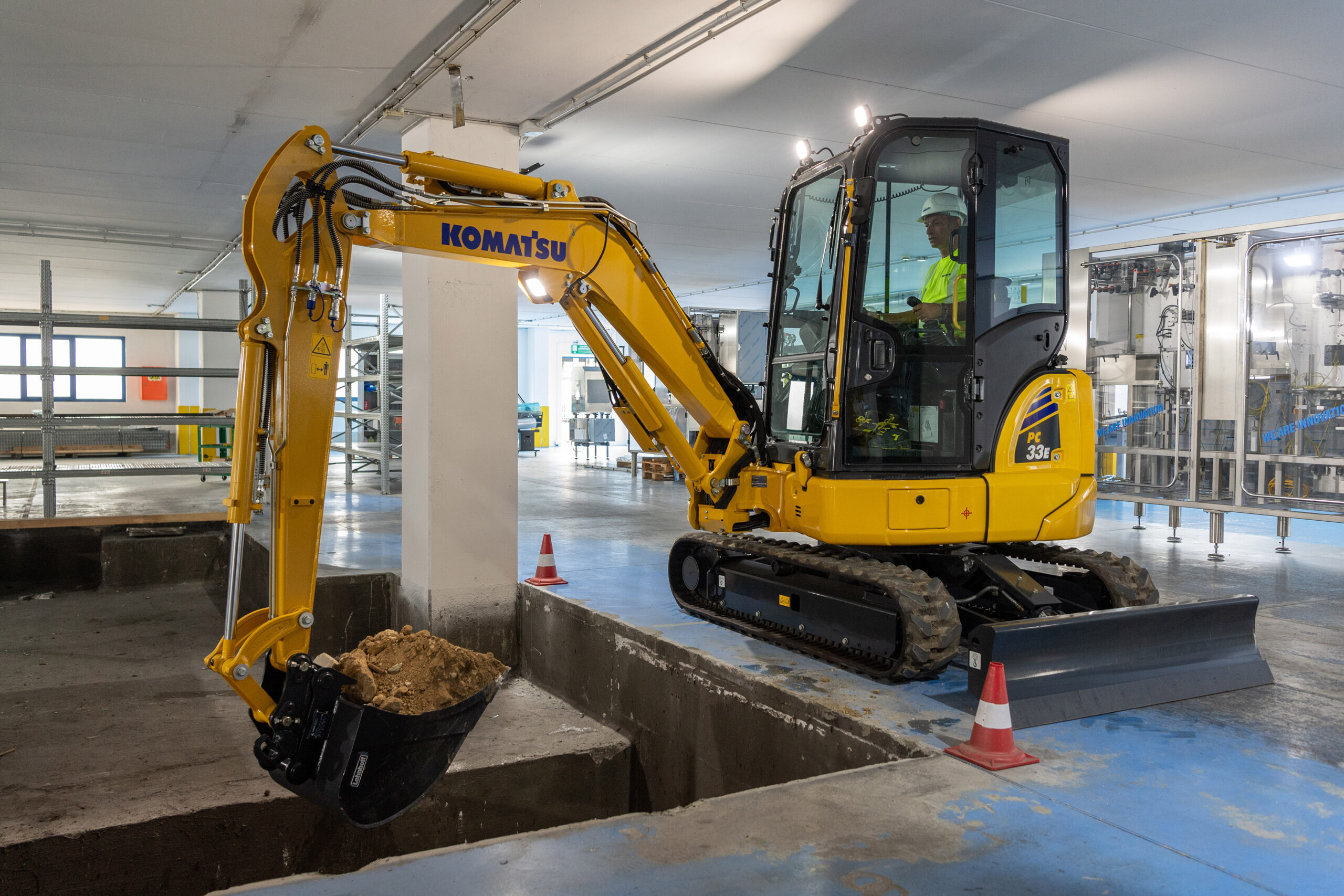 En gul komatsu-grävskopa som arbetar i en tom lokal