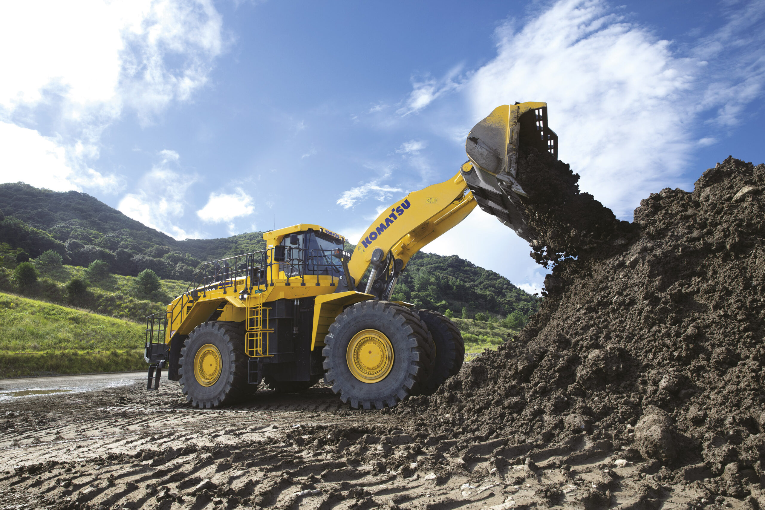 En stor komatsu-traktor dumpar jord i en hög utomhus